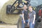 Junge Frauen in der Landwirtschaft stehen vor einem Traktor
