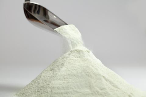 Mit einer Kelle wird Milchpulver aufgeschüttet