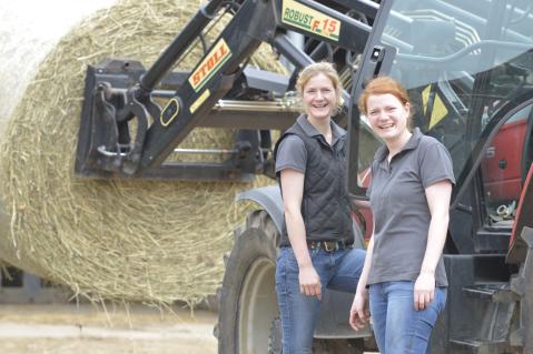 Junge Frauen in der Landwirtschaft stehen vor einem Traktor
