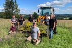 MoNaKo-Projektmitarbeiter begutachten eine Umweltmaßnahme auf einer Wiese vor einem Traktor
