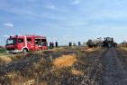 Feuerwehrauto und Traktor mit Güllefass auf einem verbrannten Getreidefeld